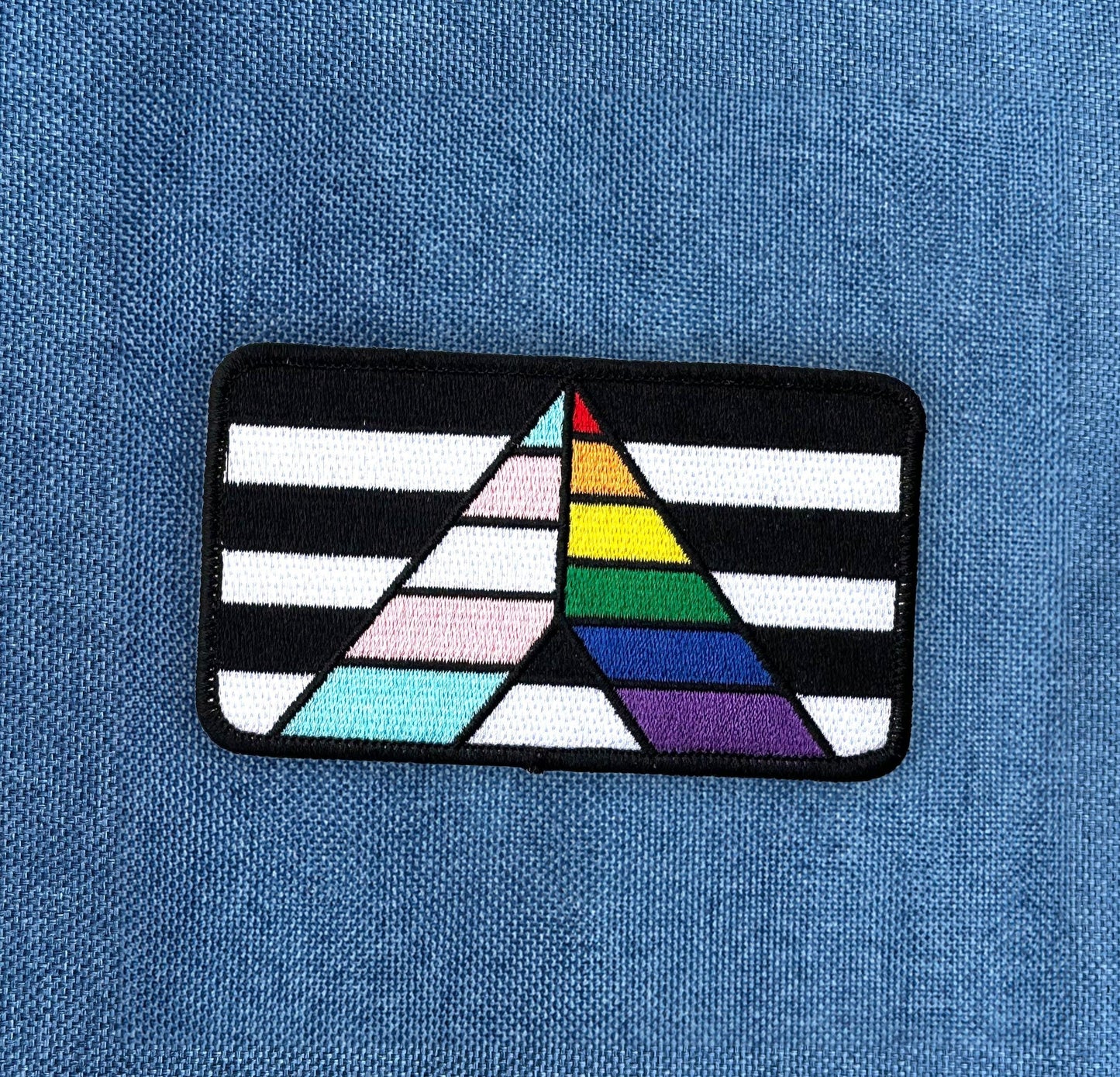 Ally Flag Embroidered Patch with Rainbow Flag and Transgender Flag motif. Shown on denim background.